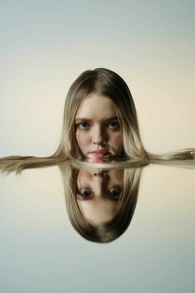 Artistic close-up portrait of a young woman reflecting in water.